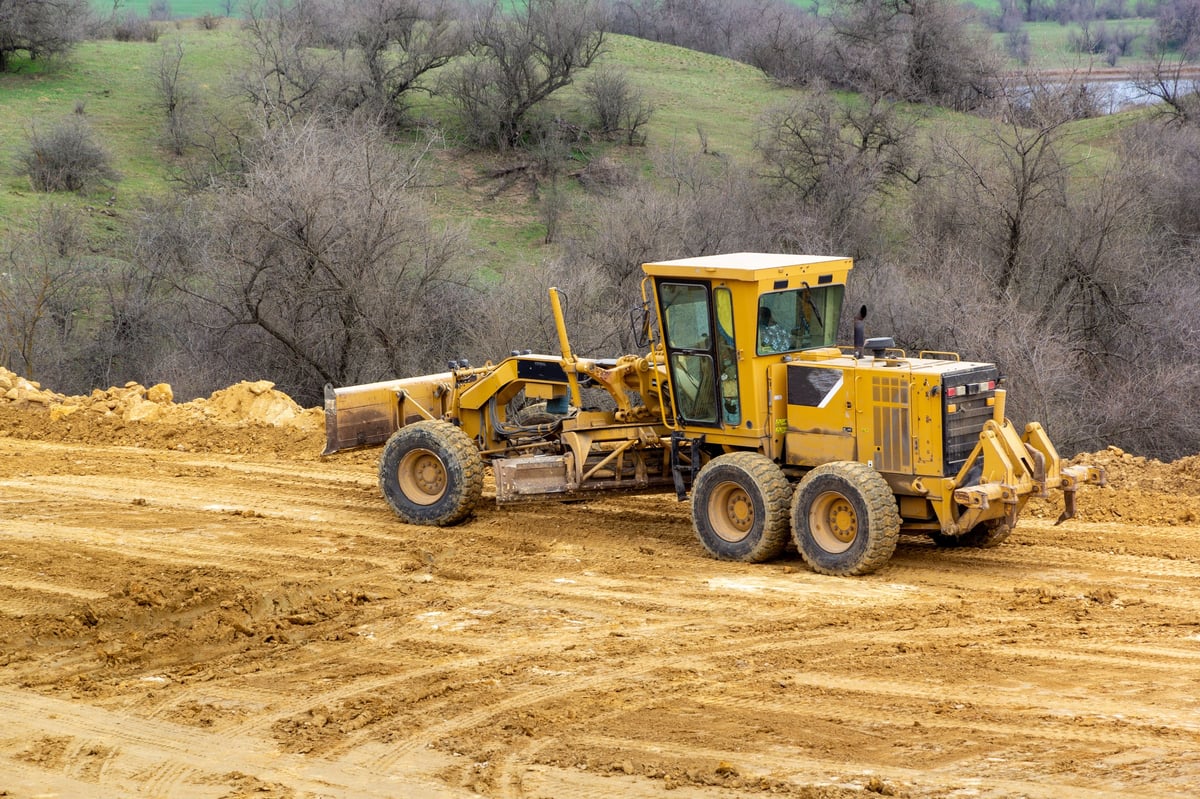 Motor grader leveling a road on a development site